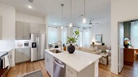 Located at 8100 Brewer Blvd in Fort Worth, TX, this single-story, 2-bedroom, 2-bathroom home offers a thoughtfully designed open-concept layout finished with warm light wood flooring, crisp white walls, and contemporary details throughout. The welcoming entrance flows into a bright hallway equipped with a smart home panel, leading to the main living areas. The kitchen is a standout feature, showcasing grey shaker cabinets, white quartz countertops, a center island with an undermount sink, stainless steel appliances, subway tile backsplash, and pendant lighting overhead. The kitchen opens seamlessly to the dining area and living room, where large windows dressed in sheer curtains fill the space with natural light. A ceiling fan adds comfort to the living room. The primary bedroom features deep teal accent walls, a large window, and direct access to a private en-suite bathroom complete with a glass-enclosed shower, a soaking tub, and a double-sink vanity. The second bedroom mirrors the sophisticated teal palette and is served by a well-appointed second bathroom. Additional spaces include a pantry, dedicated laundry room, hallway, and three closets, ensuring ample storage. The overall ambiance is modern, clean, and inviting.