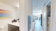 This modern studio unit at 55 Chapel St S in Hartford, Connecticut, offers a thoughtfully designed open-concept layout that maximizes every square foot. The main living area seamlessly integrates the sleeping, lounging, and dining spaces into a single cohesive room, anchored by light hardwood flooring and a floor-to-ceiling window that floods the interior with natural light and frames sweeping urban views of the Hartford skyline.

The full kitchen lines one wall and features stainless steel appliances, including a refrigerator, range with oven, built-in microwave, and dishwasher. Dark wood lower cabinetry is paired with crisp white upper cabinets and a white subway tile backsplash, creating a clean, contemporary aesthetic with ample storage.

The bathroom is finished with the same modern sensibility, showcasing a floating dark wood vanity with a white countertop, a large mirror, and light wood-toned tile flooring. The overall design is clean and functional.

Throughout the unit, a neutral white palette is complemented by light wood tones, with pendant and recessed lighting providing warm illumination. The open layout and large window contribute to an airy, bright atmosphere, making this a well-appointed urban studio in downtown Hartford.