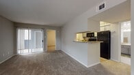 This single-story residence offers a practical and well-organized layout designed for comfortable everyday living. The living area serves as the central gathering space, finished with neutral-toned carpet and anchored by a sliding glass door fitted with vertical blinds that allows natural light to filter in while providing access to an outdoor patio area. A pass-through opening connects the living space to the kitchen, which features wood-look hard surface flooring, gray cabinetry, granite-style countertops, and a full suite of black appliances including a refrigerator, range, and microwave. The galley-style kitchen layout maximizes efficiency while maintaining an open feel toward the main living space.

The bedrooms are carpeted and generously sized, each equipped with ceiling fans and access to closet storage. At least one bedroom connects directly to a walk-in closet with built-in shelving, providing ample organization. The primary bathroom features a wide vanity with gray cabinetry, granite-style countertops, and a large mirror, while a secondary bathroom includes wood-look flooring and a shower with a curtain enclosure. A dedicated hallway connects the bathroom to additional storage and living areas. Throughout, neutral wall tones and clean white trim create a cohesive, move-in ready atmosphere.