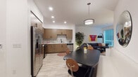 Located at 22121 Clarendon St in Woodland Hills, Los Angeles, this contemporary 1-bedroom residence showcases a thoughtfully designed single-level layout with modern finishes throughout. The open-concept kitchen is a standout feature, outfitted with warm wood-grain cabinetry, matte black hardware, white quartz countertops, and a classic subway tile backsplash. Stainless steel appliances — including a French door refrigerator, electric range, over-the-range microwave, and dishwasher — complete the fully equipped space. A sleek dark-topped dining table with modern chairs sits just off the kitchen, illuminated by a contemporary pendant light, creating a seamless transition into the living area. The living room offers a comfortable, light-filled setting with large windows dressed in horizontal blinds that invite natural light and outdoor views. Light wood-style flooring flows throughout the main living spaces, while plush carpet adds warmth to the bedroom. The bedroom features a generous walk-in closet, a window with outdoor views, and clean white walls. The bathroom is finished with a floating wood vanity, white quartz countertop, undermount sink, matte black faucet, and a large LED-backlit mirror, lending a polished, spa-like feel to the space.