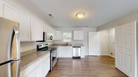 Located at 2500 W 5th St in Greenville, NC, this single-floor unit is part of a brick-exterior building with covered walkways and metal staircase access. Inside, hardwood-style flooring runs consistently throughout, providing a cohesive and clean aesthetic.

The kitchen is a standout feature, outfitted with crisp white shaker-style cabinetry, granite-look countertops, and a full suite of stainless steel appliances including a refrigerator, electric range, over-the-range microwave, and dishwasher. A window above the sink allows natural light to brighten the space. The kitchen opens to an adjacent living or dining area, creating a practical and connected layout.

The bedrooms are comfortably sized, each equipped with ceiling fans, hardwood-style flooring, windows with blinds for natural light, and closets with built-in shelving for organized storage. Neutral gray walls contribute to a calm, versatile ambiance throughout.

The unit includes two full bathrooms, each featuring a tub/shower combination, white vanity with storage, and hardwood-style flooring. One bathroom benefits from a window above the tub, bringing in additional natural light. A louvered storage closet provides extra utility within the bathroom space. The overall interior presents a clean, updated, and move-in-ready environment.