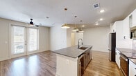 Located in Grapevine, TX, this single-story home offers a thoughtfully designed layout across three bedrooms and two bathrooms. The open-concept kitchen and living area serves as the heart of the home, anchored by a large central island topped with granite countertops and an undermount sink with a matte black faucet. Brass pendant lights hang above the island, complementing stainless steel appliances, white shaker-style cabinetry with glass-front upper panels, and a neutral tile backsplash. Wood-look flooring flows throughout the main living areas, adding warmth and cohesion.

The primary bedroom offers a comfortable retreat with a ceiling fan, ample natural light, and a walk-in closet featuring built-in shelving and hanging rods. The primary bathroom includes a glass-enclosed walk-in shower with granite detailing and brushed nickel fixtures. Additional bedrooms feature plush carpeting, ceiling fans, and windows that bring in natural light. One bedroom includes French doors that open to an outdoor view.

The laundry room is well-equipped with in-unit washer and dryer connections, overhead cabinetry, and a built-in mudroom bench with hooks and cubbies for added storage and organization.