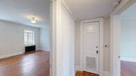 Located on Hillsborough Street in Raleigh, NC, this three-bedroom, one-bathroom home blends classic character with functional design. Rich hardwood floors run throughout, complemented by crown molding and clean white walls that lend a timeless, cohesive aesthetic across every room.

The entry hallway opens naturally into the living areas, where flush-mount globe light fixtures and large windows with blinds allow ample natural light to fill each space. The spacious primary bedroom offers generous room, while the two additional bedrooms each feature hardwood floors, natural light, and cast-iron radiators that speak to the home's period charm.

The galley-style kitchen is thoughtfully appointed with white cabinetry, granite countertops, a stainless steel sink, open wood shelving, and black and stainless appliances. A window above the counter brings in additional light and ventilation.

The bathroom showcases classic details including white hexagonal tile flooring, white subway tile surround, a soaking tub with an overhead rain shower fixture, and a clean white vanity — creating a bright, vintage-inspired retreat.

Throughout the home, the consistent use of warm hardwood floors, neutral tones, and traditional architectural details creates an inviting and cohesive living environment well-suited to Raleigh's vibrant Hillsborough Street corridor.