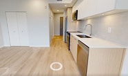 This 310 square foot studio apartment, situated at 505-3600 Sexsmith Road in Richmond, exemplifies efficient urban living. The single-floor layout maximizes space utilization, comprising a modern kitchen, a well-appointed bathroom, and a versatile main living area. The kitchen is a highlight, featuring sleek white upper cabinets contrasted with light wood lower cabinets, stainless steel appliances, and under-cabinet lighting. It includes a built-in microwave, oven, and dishwasher, optimizing functionality in a compact space. The bathroom boasts a large vanity with ample storage, a modern fixture, and a spacious mirror, complemented by marble-like tiling. Light wood flooring throughout creates a sense of continuity and brightness, while recessed lighting adds to the contemporary ambiance. The main living area, with its clean lines and minimalist design, offers flexibility for various furniture arrangements. A closet with sliding doors provides essential storage. The neutral color palette, dominated by whites and light woods, enhances the sense of spaciousness in this efficiently designed urban dwelling.