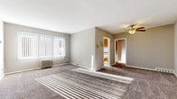 Located at 14188 Cedar Rd in University Heights, Ohio, this single-floor unit offers a practical and comfortable layout with a neutral color palette throughout. The generously sized living area is finished with plush carpet and features a large window with vertical blinds that allows abundant natural light to stream in, creating bright, sun-drenched patterns across the floor. A wall-mounted HVAC unit provides climate control, and a ceiling fan with light fixture adds airflow and warmth to the space.

The kitchen is efficiently designed with warm oak cabinetry, dark laminate countertops, and wood-look vinyl flooring. It is equipped with a refrigerator, dishwasher, and a double-basin sink beneath a window that brings in additional natural light.

The bedrooms are carpeted and well-sized, each benefiting from ceiling fans and ample closet storage with warm wood-toned sliding doors. Natural light filters into each room, enhancing the airy feel.

The bathroom features a full tub and shower combination with a window for ventilation, a single-sink vanity with white cabinetry, and wood-look flooring accented by classic pink tile detailing. The overall layout is functional and straightforward, suited for comfortable everyday living.