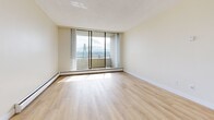 Located at 102-120 Agnes St in New Westminster, BC, this two-bedroom unit is spread across a single floor with a well-organized layout. Light wood flooring runs throughout the space, lending a warm and cohesive feel to every room.

The combined kitchen and living area forms the heart of the unit. The galley-style kitchen is outfitted with white cabinetry, granite-style countertops, stainless steel appliances including an electric range and refrigerator, and a double-basin sink beneath track lighting. The living area flows naturally from the kitchen and opens onto a private balcony through floor-to-ceiling sliding glass doors, offering views of the surrounding landscape, including a notable bridge and waterway.

The primary bedroom is generously proportioned and features large windows that frame outdoor views and allow abundant natural light to fill the room. It includes a built-in closet with shelving and a mirrored sliding door. The second bedroom is similarly bright, with a large window and a mirrored closet. Both bedrooms are served by baseboard heating throughout.

The bathroom features a granite-topped vanity with white cabinetry, warm wood-toned upper storage, and light wood flooring. A welcoming hallway with multiple closets connects all areas of the unit, providing excellent storage capacity throughout.