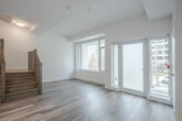 Located at 55 Quebec Ave in Toronto's vibrant Junction neighbourhood, this two-storey unit offers 2 bedrooms and 3 bathrooms across two well-proportioned floors. The main level features an open-concept layout combining the living, dining, and kitchen areas, all finished with light hardwood-style flooring. The contemporary kitchen is equipped with stainless steel appliances, two-tone cabinetry, a patterned tile backsplash, and a freestanding island with built-in shelving, topped with a white quartz-style surface and accented by a modern pendant light. Large windows and a glass-panel door on the main floor flood the space with natural light and provide direct access to the balcony, offering outdoor views of surrounding greenery and the neighbourhood streetscape. A wood-railed staircase connects both floors. The upper level houses the two bedrooms, including a generously sized primary bedroom, alongside the remaining bathrooms. The bathrooms are finished in a clean, modern style — one featuring a double-sink vanity with light wood cabinetry and large mirrors, and another with a soaker tub surrounded by floor-to-ceiling neutral stone-look tile. Throughout, the unit maintains a bright, minimalist aesthetic with white walls and contemporary finishes.