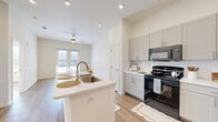 Located at 740 14th Street in Plano, TX, this thoughtfully laid-out one-bedroom, one-bathroom residence offers a bright and modern living experience across a single floor. The open-concept kitchen and living room serve as the heart of the home, anchored by a central island with a white quartz countertop and a stainless steel sink. The kitchen is equipped with gray shaker-style cabinetry reaching toward the ceiling, a white subway tile backsplash, and black appliances including a range, microwave, and refrigerator. Light wood-tone flooring flows throughout the space, complementing the crisp white walls and recessed lighting. The living area opens to French doors that invite natural light and provide access to an outdoor area, while a ceiling fan adds comfort overhead. The bedroom is a serene, generously proportioned retreat featuring a bank of windows with exterior views and continued wood-tone flooring. The bathroom offers a clean, spa-like aesthetic with gray cabinetry, a wide white vanity countertop, a well-lit mirror, and a tiled shower with subtle teal accent tiles. Additional spaces include a pantry, laundry area, and two closets, providing ample storage throughout this efficiently designed and well-appointed home.