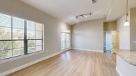 Located at 18545 University Blvd in Sugar Land, TX, this well-appointed one-bedroom, one-bathroom unit offers a thoughtfully designed single-floor layout. Light wood-style flooring flows throughout, complementing the neutral warm-gray walls and crisp white trim found across every room.

The living room is bright and airy, featuring vaulted ceilings, track lighting, and abundant natural light from multiple windows with blinds. French doors open to an outdoor area, enhancing the sense of openness. The dedicated entrance area also benefits from vaulted ceilings and a large window, creating a welcoming first impression.

The kitchen is well-equipped, showcasing rich dark-wood cabinetry extending to the ceiling, granite countertops, and a full suite of stainless steel appliances including a refrigerator, range, and microwave. An adjacent walk-in pantry with built-in shelving provides generous storage.

The spacious primary bedroom features a ceiling fan, large window with outdoor views, and direct access to two closets and the full bathroom. The bathroom is finished with tile-surround tub and shower combination, dark wood cabinetry, and a vanity with mirror. A dedicated laundry area with an in-unit washer rounds out this functional and comfortable home.