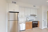 Located at 507 Kennedy St NW in Washington, DC's Petworth neighborhood, this modern one-bedroom, one-bathroom unit offers a well-designed, efficient layout across a single floor. The open-plan living, dining, and kitchen area serves as the heart of the unit, bathed in natural light from large corner windows that frame street-level views of the surrounding neighborhood. Light hardwood flooring runs throughout the main living areas and bedroom, contributing to a bright, cohesive aesthetic.

The kitchen is thoughtfully outfitted with stainless steel appliances — including a full-size refrigerator, dishwasher, and electric range — complemented by white upper cabinetry, warm wood lower cabinets, and a clean tile backsplash. Recessed lighting and ample upper storage complete the functional space.

The bedroom is a well-proportioned private retreat with its own window, light hardwood floors, and a dedicated closet. The bathroom features accessibility-friendly grab bars, hexagonal tile flooring in a warm gray tone, a wood-accented vanity with a white countertop, and a walk-in shower. An in-unit laundry area adds everyday convenience. The unit's clean, contemporary finishes and abundance of natural light make it a practical and comfortable urban residence.