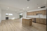 Unit 402 at 4210 Spring St in La Mesa, California offers a clean, modern design characterized by crisp white walls, light wood-style flooring, and an abundance of natural light throughout. The open-concept living and kitchen area serves as the heart of the unit, where warm wood cabinetry, white quartz countertops, a center island, and stainless steel appliances — including a refrigerator, dishwasher, and range — come together in a functional and stylish layout. Recessed lighting complements the natural brightness pouring in through large sliding glass doors. Those doors lead to a private balcony finished with a wood-beamed pergola overhead and black metal railings, offering sweeping panoramic views of La Mesa's rolling hills and the surrounding neighborhood skyline. The bedrooms are bright and well-proportioned, each benefiting from windows framing the same scenic hillside views, with light-toned flooring continuing throughout. A walk-in closet provides generous storage. The bathroom features a full soaking tub and shower combination with clean white tile surround, a wood-finish vanity, and a lighted mirror. An in-unit stacked washer and dryer adds everyday convenience. The overall ambiance is fresh, airy, and move-in ready.