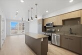 This contemporary single-floor residence at 1367 Miller Avenue in Millcreek, Utah, showcases a harmonious blend of modern design and functional living spaces. The interior is characterized by its bright, airy atmosphere, enhanced by large windows that flood the rooms with natural light. 

The home boasts light-toned hardwood flooring throughout, creating a seamless flow between spaces. The kitchen is a standout feature, equipped with state-of-the-art stainless steel appliances, sleek cabinetry in neutral tones, and a central island with a waterfall countertop, perfect for casual dining or food preparation.

The bathroom exudes luxury with its pristine white tiles, modern fixtures, and a spacious bathtub. The bedroom areas are generously sized, with ample closet space and large windows offering views of the surrounding area.

French doors in one of the rooms lead to what appears to be an outdoor space, potentially a balcony or patio, further expanding the living area. The home's overall design emphasizes clean lines, neutral color palettes, and a minimalist aesthetic, creating a sophisticated and inviting living environment.

Recessed lighting and pendant fixtures add to the modern ambiance, while the open floor plan promotes a sense of spaciousness and flexibility in use of the areas. This residence is ideal for those seeking a contemporary lifestyle in the heart of Millcreek.