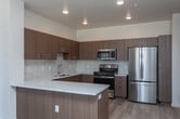 Located at 713 N Main St in Meridian, Idaho, this single-floor 2-bedroom, 2-bathroom residence offers a clean, modern aesthetic with thoughtfully designed living spaces. Light-toned luxury vinyl plank flooring flows throughout, creating a cohesive and easy-to-maintain foundation across every room.

The kitchen is a standout feature, showcasing warm wood-grain cabinetry, white quartz countertops, a marble-style tile backsplash, and a full suite of stainless steel appliances including a French door refrigerator, gas range with over-the-range microwave, and dishwasher. A generous island provides additional prep and seating space, while recessed lighting enhances the bright, open atmosphere.

The living area is open and airy, anchored by a wall-mounted mini-split HVAC unit for efficient climate control. Both bedrooms are well-proportioned with ample natural light from large windows that offer views of the surrounding neighborhood. One bedroom includes a dedicated closet accessible via a paneled door.

Each bathroom is finished with warm wood-tone vanities, white quartz countertops, large mirrors with statement pendant lighting, and clean white fixtures. One bathroom features a walk-in shower, while the second includes a full soaking tub and shower combination. The overall design is bright, modern, and move-in ready.