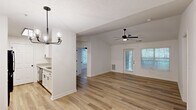 This single-story, 2-bedroom, 1-bathroom home in Columbus, Georgia offers a clean, modern aesthetic throughout. The open-concept living and dining area is anchored by warm wood-look luxury vinyl plank flooring, a ceiling fan with light fixture, and a stylish multi-bulb chandelier. Natural light pours in through large windows and a glass-panel back door fitted with blinds, creating a bright and welcoming atmosphere.

The galley-style kitchen is thoughtfully designed with crisp white shaker cabinets, granite countertops, black matte hardware, and black appliances including a refrigerator, electric range, and microwave. A pass-through window connects the kitchen to the living area, enhancing the open feel. The kitchen also provides direct access to a utility room.

Both bedrooms feature plush carpet flooring, ceiling fans, and ample natural light from windows with blinds. The spacious primary bedroom includes vaulted ceilings and a dedicated closet. The full bathroom is finished with granite countertops, wood-look flooring, white cabinetry with black hardware, and a tub/shower combination. Consistent use of black matte fixtures and neutral tones gives the entire home a cohesive, updated look.