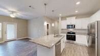 This single-story home in Chester, VA offers a well-designed layout featuring three bedrooms, two bathrooms, and a dedicated laundry room. The open-concept kitchen and living area serves as the heart of the home, highlighted by a central island with granite countertops, an undermount double sink, and pendant lighting overhead. White shaker-style cabinetry extends to the ceiling, complemented by stainless steel appliances including a range, built-in microwave, and refrigerator. Recessed lighting and wood-look flooring complete the kitchen's clean, modern aesthetic.

The living area flows seamlessly from the kitchen, offering an open and versatile space. The bedrooms feature plush carpeting and ceiling fans, with the primary bedroom providing access to two separate rooms, likely a bathroom and closet. Additional bedrooms include windows that allow natural light and views of the surrounding area.

Both bathrooms are finished with granite-topped vanities and wood-look flooring. One bathroom includes a walk-in shower. The dedicated laundry room houses a full-size washer and dryer with overhead wire shelving for additional storage. Three closets throughout the home provide ample storage across the layout.
