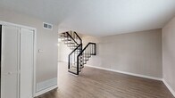 Located in Sandy Springs, GA, this two-bedroom, two-bathroom residence spans two floors, offering a practical and well-appointed layout. The main floor hosts the combined kitchen and living area, where warm hardwood-style flooring flows throughout. The kitchen stands out with crisp white shaker cabinetry, marble-style countertops, a double-basin sink, and black appliances including a range and full-size refrigerator. The adjacent living room is bright and open, with a large window that brings in natural light and views of the surroundings. The generously sized primary bedroom is located on the main level and features hardwood-style flooring, a closet with mirrored sliding doors, and direct access to a full bathroom. The upper floor houses two additional carpeted bedrooms, each equipped with ceiling fans and windows for natural ventilation and light. A full bathroom on this level includes a tub-shower combination with white tile surround. Throughout the home, neutral warm-gray tones on the walls create a cohesive and understated aesthetic. A dedicated staircase connects the two floors, and a closet provides additional storage. The overall design is clean, functional, and move-in ready.