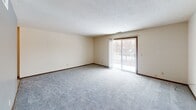Located at 4905 W Victoria Dr in Sioux Falls, South Dakota, this single-floor unit offers a practical and comfortable layout across several well-defined living spaces. The living area is generously sized, featuring neutral-toned carpet, cream-colored walls, and a textured ceiling. A sliding glass door fills the room with natural light and opens to a private balcony, offering views of the surrounding neighborhood. An adjacent area connects seamlessly to the rest of the unit, providing a flexible open flow. The galley-style kitchen is efficiently designed with warm wood cabinetry, light countertops, a double sink, and tile flooring. White appliances including a refrigerator and range complete the functional cooking space. The bedrooms are carpeted and feature neutral walls, textured ceilings, and ample closet space with built-in shelving. Natural light enters through windows fitted with blinds. The bathroom is well-appointed with a single vanity, large mirror with overhead lighting, mosaic tile flooring, and a tub-shower combination. A separate shower stall with classic white tile provides additional bathing options. Wood-tone trim and baseboards throughout the unit add a cohesive, traditional character to the overall design.