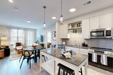 Located at 410 E 7th St in Frederick, MD, this well-appointed 2-bedroom, 2-bathroom residence offers a thoughtfully designed open-concept layout on a single floor. The kitchen is a standout feature, boasting crisp white cabinetry, a gray tile backsplash, dark quartz countertops, stainless steel appliances, and a central island with pendant lighting — ideal for both cooking and casual dining. The space flows seamlessly into the combined dining and living area, where large windows invite abundant natural light and provide views of the surrounding neighborhood. The living room is bright and welcoming, with access to a private balcony overlooking the vibrant streetscape of Frederick's growing East Side. The primary bedroom is generously sized, featuring plush carpeting, a large window, and a spacious walk-in closet with wire shelving. The bathrooms are finished with light wood vanities, white quartz countertops, and large-format tile flooring, lending a clean, modern aesthetic. Three closets throughout the unit provide ample storage, and an in-unit laundry area adds everyday convenience. Light wood-tone flooring runs through the main living areas, tying the contemporary design together cohesively.