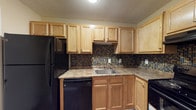 Located at 10612 Abercorn Extension in Savannah, GA, this single-floor unit offers a well-organized and functional layout throughout. The kitchen is a standout feature, outfitted with light oak cabinetry, granite-style countertops, and a striking mosaic tile backsplash in shades of blue, gold, and brown. Black appliances, including a refrigerator, dishwasher, and range, complement the warm tones of the cabinetry, while a stainless steel sink and under-cabinet range hood add practical utility to the space.

The living area benefits from a sliding glass door dressed with vertical blinds, allowing natural light to fill the room while providing access to the outdoors. Rich, dark hardwood-style flooring runs throughout the living and bedroom areas, creating a cohesive and inviting aesthetic. The bedroom features the same flooring, neutral wall tones, crisp white baseboards, and a ceiling fan with a built-in light fixture, ensuring year-round comfort.

The bathroom is clean and well-appointed, featuring a full tub and shower combination with white tile surround and chrome fixtures, a granite-style vanity countertop, and a textured ceiling consistent with the rest of the unit. Overall, the space presents a comfortable and practical living environment in a convenient Savannah location.
