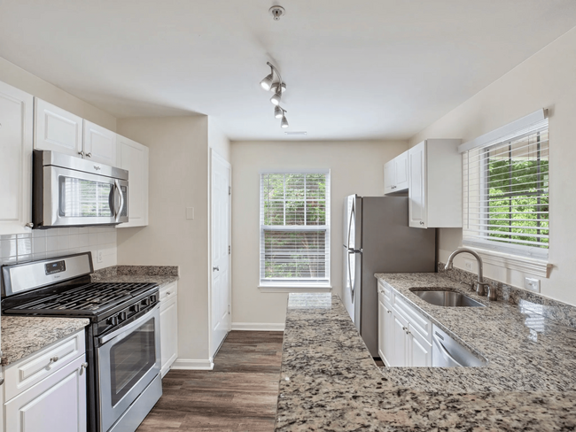 Kitchen with granite countertops and stainless steel appliances. - The Estates