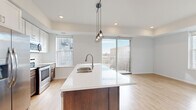 Located in the heart of downtown Fargo at 410 Fifth St N, this well-appointed 2-bedroom, 2-bathroom residence offers a thoughtfully designed single-level layout. The open-concept living and kitchen area serves as the centerpiece of the home, where light-toned hardwood-style flooring flows seamlessly underfoot. The kitchen is outfitted with stainless steel appliances, a subway tile backsplash, two-tone cabinetry featuring white upper cabinets and rich dark lower cabinets, and a spacious island with a white quartz countertop, undermount sink, and stylish pendant lighting — ideal for cooking and entertaining alike.

The living area benefits from large floor-to-ceiling windows that invite abundant natural light and frame views of the surrounding historic brick architecture of downtown Fargo. Both bedrooms are generously sized, with plush carpeting and oversized windows that continue the urban panorama. The spacious primary bedroom includes a large walk-in closet with wire shelving on three walls, providing ample storage. Each bathroom features a clean, bright tub-shower combination with chrome fixtures. A dedicated laundry room with a stacked full-size washer and dryer adds everyday convenience to this modern urban residence.