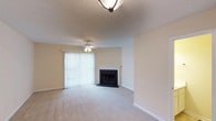 Located at 1 Dansey Ct in Durham, North Carolina, this two-story residence offers a comfortable and functional layout designed for everyday living. The living room serves as the heart of the home, featuring a classic fireplace with a clean white mantle and dark surround that anchors the space as a natural focal point. Plush wall-to-wall carpeting runs throughout, adding warmth underfoot, while neutral-toned walls create a bright and versatile backdrop. A ceiling fan with an integrated light fixture provides both comfort and illumination, complementing the flush-mount ceiling light overhead. The textured ceiling adds a subtle layer of architectural character. A sliding glass door dressed with vertical blinds floods the room with natural light and provides seamless access to the outdoors, enhancing the sense of openness. The overall ambiance is warm and inviting, with a neutral palette that offers flexibility for a variety of décor styles. Spanning two floors, the home provides ample space for comfortable living, with a layout that balances shared living areas and private retreats across its levels.