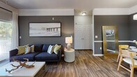 Located at 105 Breakers Dr in Myrtle Beach, SC, this single-floor residence offers a thoughtfully designed coastal-inspired interior with modern finishes throughout. The open-concept living area is highlighted by rich wood-look flooring, crown molding, and a ceiling fan, while large sliding glass doors lead to a private balcony, flooding the space with natural light. A bold accent wall anchors the living room, complemented by coastal artwork that reflects the surrounding environment.

The kitchen is well-appointed with light wood cabinetry, white countertops, black appliances, and a peninsula with bar seating, creating a functional and social cooking space. A skylight adds additional brightness to the area.

The bedroom features plush carpet flooring, a large window with ample natural light, a walk-in closet with built-in shelving, and a dedicated workspace. Coastal-themed wall art reinforces the serene atmosphere throughout.

Two bathrooms serve the unit, each featuring wood-look tile flooring, light wood vanity cabinetry, and white countertops. One bathroom includes a tub-shower combination with a classic striped curtain, while the other offers a vanity with a large mirror and easy access from the bedroom.

Overall, the space presents a clean, cohesive coastal aesthetic with practical, modern amenities.