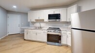 Located at 600 Sherman St in Akron, Ohio, this single-floor 2-bedroom, 1-bathroom unit offers a thoughtfully designed layout with clean, modern finishes throughout. Light wood laminate flooring runs seamlessly across all rooms, lending a bright and cohesive feel to the entire space.

The kitchen is a standout feature, outfitted with crisp white shaker-style cabinetry, granite-look countertops, and a full suite of stainless steel appliances including a gas range, over-the-range microwave, and refrigerator. A curved peninsula countertop opens toward the living area, creating an open, connected feel between the kitchen and main living space.

The living area is open and well-lit, with recessed lighting and a flush ceiling fixture providing ample illumination. Both bedrooms are comfortably sized with soft gray walls, light wood flooring, and windows that bring in natural light with views of the surrounding neighborhood. The primary bedroom includes a six-panel door and direct hallway access.

The bathroom features a full tub-shower combination with built-in shelving and brushed nickel fixtures, maintaining the clean aesthetic found throughout the home. A utility room and hallway round out the floor plan, adding practical functionality. Overall, the space presents a fresh, move-in-ready environment with consistent, updated finishes.