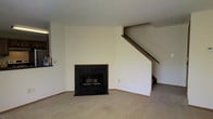 Located at 6564 Millridge Cir in Dublin, Ohio, this two-story home offers a straightforward and functional layout across two levels. The main living area serves as the heart of the home, finished with wall-to-wall carpeting that adds warmth underfoot. A standout feature of this space is the wood-framed fireplace with a black surround, providing a classic focal point and a cozy atmosphere. A textured ceiling runs throughout, lending the space a traditional residential character. Neutral, cream-toned walls keep the interior feeling bright and open, offering a versatile backdrop for a variety of décor styles. A staircase with a wooden handrail rises from the main living area, connecting seamlessly to the upper floor and adding a sense of vertical dimension to the space. A doorway off the main area provides access to additional rooms, supporting a well-connected floor plan. The overall ambiance is clean, quiet, and move-in ready, reflecting the calm residential character of the Millridge Circle neighborhood in Dublin — a well-regarded community in central Ohio known for its suburban charm and convenient access to local amenities.