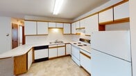 Located at 4330 Tenth Ave S in Fargo, North Dakota, this single-floor unit offers a practical and straightforward layout designed for comfortable everyday living. The kitchen is well-equipped with ample white cabinetry accented by warm wood trim, a double-basin sink, electric range, dishwasher, and a full-size refrigerator. Light tile-style flooring runs through the kitchen and entry area, providing a clean and durable surface. The living area is generously sized, featuring plush carpeting, textured ceilings, baseboard heating, and a sliding glass door fitted with vertical blinds that allow for natural light and outdoor access. A wall-mounted air conditioning unit ensures year-round climate comfort. The bedroom offers a quiet, carpeted retreat with a window overlooking greenery, fitted with horizontal blinds and supplemented by baseboard heating. The full bathroom includes a single-sink vanity with wood cabinetry, a tub-shower combination, and tile-style flooring. Throughout the unit, warm wood-trimmed doors and baseboards provide consistent detailing, while neutral wall tones and textured ceilings contribute to a clean, understated aesthetic. The overall layout is efficient and well-organized, making this a functional space in a residential Fargo neighborhood.