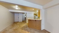 Located at 4044 Lake Crest Cir in Kalamazoo, Michigan, this single-floor residence offers a functional and straightforward layout. The open-concept kitchen is equipped with white cabinetry accented by wood trim, ample upper and lower storage, a gas range, refrigerator, and a built-in range hood. A wood-paneled peninsula separates the kitchen from the living area, providing a natural transition between the two spaces. The living area is finished with neutral wall-to-wall carpeting and features a sliding glass door that opens to an outdoor view, allowing natural light to fill the space. A large louvered double-door closet is conveniently located near the main entry, offering generous storage. The bedroom is carpeted, features a window with blinds for natural light, and includes a louvered closet door. The bathroom is fitted with tile flooring, a full soaking tub with shower, and a vanity. Recessed and flush-mount ceiling lighting is found throughout the unit, maintaining a clean and consistent aesthetic. The overall design is practical and neutral, offering a clean canvas throughout.