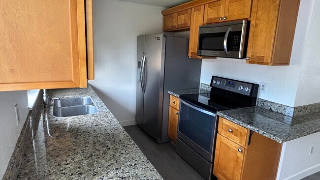 Cocina completamente renovada con estufa de vidrio, refrigerador de doble puerta, microondas y lavavajillas. - 18609 78th Ave E