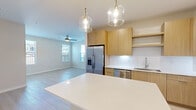 Located at 1224 Old Peachtree Rd NE in Lawrenceville, Georgia, this well-appointed 2-bedroom, 2-bathroom single-story residence offers a clean, modern aesthetic with thoughtful design throughout. Light wood-tone flooring flows seamlessly across the entire home, complementing the bright, neutral color palette that gives each room an open and airy feel.

The kitchen serves as a central highlight, featuring flat-front light wood cabinetry extending to the ceiling, white quartz countertops, a crisp tile backsplash, and a full suite of stainless steel appliances including a French door refrigerator, dishwasher, microwave, and range. A large island with pendant globe lighting overhead connects the kitchen to the living area, which is bathed in natural light from multiple windows and fitted with a ceiling fan.

Both bedrooms are generously sized, each offering ceiling fans, large windows with outdoor views, and light-filled interiors. The primary bedroom includes access to a spacious walk-in closet with multi-tiered wire shelving systems. A total of three closets provide ample storage throughout the home.

The bathrooms are finished with clean, modern fixtures, and one features a soaking tub surrounded by marble-look tile surround panels, adding an elevated touch. A connecting hallway ties the layout together efficiently, creating a functional and cohesive living space.