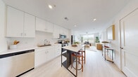 Located at 1001 Innovation Dr in Elkton, MD, this one-bedroom, one-bathroom residence offers a thoughtfully designed layout across a single floor. The open-concept living room is bathed in natural light from large windows with views of the outdoors, and features light wood-tone flooring, neutral walls, and a ceiling fan — creating a calm, airy atmosphere. The modern kitchen is outfitted with full-height white cabinetry, a light quartz countertop, stainless steel appliances including a range, microwave, dishwasher, and refrigerator, plus a freestanding island with bar seating — ideal for both cooking and casual dining. The bedroom is a comfortable, well-lit retreat with large windows, a ceiling fan, and light hardwood-style flooring. It is complemented by a generously sized walk-in closet featuring built-in wire shelving and hanging systems for ample storage. The full bathroom is clean and bright, finished in white with a tub-shower combination, a floating vanity, and light flooring that ties the space together. Throughout the residence, a consistent palette of whites and light neutrals creates a cohesive, modern aesthetic.