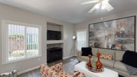 The Brook's 2-bedroom, 2-bathroom floor plan is a well-appointed single-story residence designed with both comfort and style in mind. The living room serves as the centerpiece of the home, featuring wood-style flooring, a ceiling fan, a built-in media niche, and multiple windows that invite natural light. Large-scale artwork adds a bold, contemporary touch to the space. Adjacent to the living area, the dining space is highlighted by a modern chandelier, a glass-top table, and a glass door that opens to an outdoor patio, creating a seamless indoor-outdoor connection. The kitchen is outfitted with white shaker cabinetry, granite-style countertops, stainless steel appliances, and a breakfast bar, offering both functionality and a clean aesthetic. Both bedrooms are carpeted and well-sized, each featuring ceiling fans and generous closet space. The primary bedroom includes a sliding glass door with outdoor views, while the second bedroom benefits from a bright window overlooking lush greenery. Each bathroom is finished with a white vanity, granite-style countertops, a large mirror, and wood-style flooring, maintaining a consistent and polished design throughout the home.