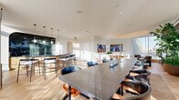 Located at 44 M St NE in Washington, DC, this elegantly designed amenity space spans a single floor and offers a refined, multi-functional environment for gathering and recreation. The layout encompasses two distinct living areas, a connecting hallway, and a series of thoughtfully curated spaces that blend luxury with comfort.

The centerpiece of the space is a dramatic bar and lounge area anchored by a curved counter finished in rich dark green marble, set against a matching marble-clad arched alcove. Warm-toned pendant lighting and a herringbone hardwood floor throughout lend a cohesive, upscale aesthetic. Bar-height seating and a large communal dining table make the space ideal for both casual and formal gatherings.

The main living area features a sweeping tray ceiling, plush seating arrangements, and floor-to-ceiling glass walls that flood the interior with natural light and offer expansive outdoor views. A second, more intimate lounge area is distinguished by sage-green walls, arched architectural niches with built-in banquette seating, and a full billiards table — offering a relaxed, game-room atmosphere.

A dedicated dining zone with a sleek dark table and orange-accented chairs is bathed in sunlight from wraparound glass walls. Throughout, the space maintains a cohesive design language of warm woods, sculptural furnishings, and curated artwork.