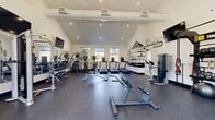 Located at 7900 Southeast Luther Road in Portland, OR, this 990-square-foot fitness center is a single-floor facility thoughtfully designed to support a comprehensive workout experience. The space features striking vaulted ceilings with recessed lighting that amplify the open, airy atmosphere, while large windows along the walls invite abundant natural light and views of the surrounding greenery.

The gym is outfitted with a diverse range of equipment to accommodate various fitness goals. Cardio offerings include treadmills, ellipticals, and stationary bikes, while strength training needs are met with a cable machine, a multi-function cable/weight station, a dumbbell rack stocked with a full range of weights, kettlebells, medicine balls, and a stability ball. A dedicated training zone provides additional functional fitness options.

Full-length mirrors line one wall, both enhancing the sense of space and allowing for proper form checks during workouts. Durable rubber flooring covers the entire area, ensuring safety and comfort. Motivating Pacific Northwest-themed graphic murals adorn the walls, giving the space a distinctive and energetic character. Multiple flat-screen TVs are mounted throughout, adding entertainment value during workouts. The facility also includes a large glass door entry, providing easy access and additional natural light.