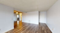 This single-floor unit offers a straightforward and functional layout across several well-defined living spaces. The main living area features wood-style laminate flooring, neutral white walls, and a textured ceiling, creating a clean and open atmosphere. A ceiling fan provides additional comfort, and the space flows openly into adjacent areas, making it feel connected and accessible.

The kitchen is efficiently arranged in a galley style, featuring white cabinetry, dark countertops, tile flooring, and a double-basin sink. A large window with vertical blinds allows natural light to fill the space while providing views of the surrounding outdoor environment. An electric range and oven are included for full cooking functionality.

The bedrooms are carpeted for comfort, with neutral tones throughout. One bedroom includes a built-in closet with adjustable shelving and hanging rods, offering practical storage. A second room with wood-style flooring provides additional flexible living space.

The bathrooms are finished with white tile flooring. One full bathroom includes a tub-shower combination with a curved curtain rod, a toilet, and a vanity with a mirror. A second, more compact bathroom provides additional convenience.

Overall, the unit presents a clean, no-frills living environment with consistent finishes, practical storage solutions, and natural light in key areas.