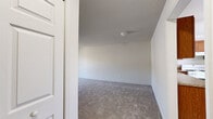 Located at 504 Sherwood Dr S in Middletown, NY, this 3-bedroom, 1-bathroom residence offers a practical and comfortable single-floor layout. The living area features soft carpeting and a sliding glass door that opens to a balcony, inviting natural light and outdoor views of the surrounding trees. The kitchen is well-appointed with warm-toned wooden cabinetry, granite-style countertops, white appliances including a gas range, refrigerator, and dishwasher, and clean white tile flooring. A ceiling fan with a light fixture adds comfort to the space, while a window provides additional natural light. The generously sized primary bedroom offers ample room, with plush carpeting and a closet with built-in shelving for storage. The additional bedrooms are carpeted and feature windows with blinds that bring in natural light. The shared bathroom includes a full tub-shower combination with floor-to-ceiling stone-style tile, providing a clean and classic finish. A dedicated laundry area and a hallway connecting all rooms round out this functional layout, making it a well-organized and livable home.