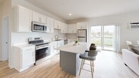 Located at 160 Ash Street East in Annandale, Minnesota, this well-appointed 2-bedroom, 2-bathroom single-floor unit offers a thoughtfully designed layout with modern finishes throughout. The open-concept living, dining, and kitchen area serves as the heart of the home, bathed in natural light from large windows and a sliding glass door that opens to views of the landscaped grounds. The kitchen is outfitted with crisp white shaker cabinets, a light quartz-topped center island with seating, stainless steel appliances including a range, microwave, dishwasher, and refrigerator, all set above light wood-style vinyl plank flooring. The living area features a neutral, bright palette with natural light and a cozy, functional layout. The primary bedroom offers plush carpeting, a wall-mounted AC unit, baseboard heating, and a closet with sliding panel doors and built-in shelving. The bathrooms are finished with white cabinetry, quartz countertops, and a walk-in shower with clean tile surround. Additional features include four closets, a dedicated laundry area, and a connecting hallway. The building exterior showcases contemporary board-and-batten siding with well-maintained communal outdoor spaces.