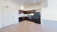 Located in National City, CA, this single-story home offers four bedrooms and two full bathrooms within a thoughtfully arranged floor plan. Light-toned hardwood flooring flows consistently throughout, lending warmth and visual continuity to every room.

The kitchen is a functional standout, featuring rich dark-wood cabinetry with modern hardware, light quartz countertops, recessed lighting, and black appliances including a range, microwave, and refrigerator. The open sightlines from the kitchen to adjacent areas make the space feel connected and accessible.

Each bedroom is finished with the same hardwood flooring and neutral cream-toned walls, creating a clean and versatile backdrop. Natural light filters in through windows dressed with vertical blinds, brightening each room. Select bedrooms include sliding panel closets with contemporary hardware for efficient storage.

The two bathrooms maintain the home's clean aesthetic with white tiled tub-shower combinations, hardwood-style flooring, and dark-wood vanities topped with stone-finish counters. One bathroom features a window with vertical blinds for added ventilation and light.

A connecting hallway links the bedrooms and bathrooms, maintaining an efficient flow through the home. Throughout, crisp white trim and consistent finishes give the space a cohesive, move-in ready feel.