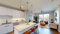 Located in Scottsdale, AZ, this well-appointed 2-bedroom, 2-bathroom single-floor residence offers a thoughtfully designed open-concept layout. The entrance welcomes you with a decorative round mirror and smart thermostat, leading into the heart of the home. The modern kitchen is a standout, featuring sleek flat-front white cabinetry extending to the ceiling, stainless steel appliances including a gas range, microwave, refrigerator, and dishwasher, complemented by a white tile backsplash, black matte fixtures, and a large center island with seating for three. Gold cylindrical pendant lights add an elegant touch overhead. Wood-look flooring flows throughout the space. The living room is bright and inviting, with a ceiling fan, large sliding glass doors that open to a private balcony overlooking the surrounding neighborhood. The primary bedroom is a comfortable retreat with a ceiling fan and dedicated walk-in closet featuring multi-tier shelving. The primary bathroom offers a dual-sink vanity with white cabinetry, a framed mirror, and a glass-enclosed walk-in shower with marble-style tile and matte black hardware. The second bedroom is bright with a large window and a ceiling fan. Both bedrooms include individual closets for ample storage.