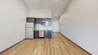 Located at 3001 34th Ave S, Unit 3C in Fargo, ND, this 340-square-foot single-floor studio apartment offers a functional and modern living space. The open-concept layout seamlessly combines the living and kitchen areas, finished with warm-toned luxury vinyl plank flooring and neutral light gray walls throughout, creating a clean, contemporary aesthetic. Dark charcoal baseboard trim provides a subtle contrast to the light-colored walls.

The kitchen is well-appointed with dark espresso cabinetry, a stainless steel refrigerator, dishwasher, and over-the-range microwave, complemented by light countertops and a single-basin sink. Recessed lighting illuminates both the kitchen and the open living area, which also features a wall-mounted PTAC heating and cooling unit beneath a window that allows natural light to enter the space. An electrical panel is conveniently accessed near the entry door.

The bathroom features a wide, wall-mounted vanity with a vessel-style sink, a large mirror with overhead lighting, and light-toned flooring, delivering a bright and clean environment. This compact, efficiently designed unit is well-suited for a single occupant seeking a low-maintenance, move-in-ready residence in Fargo.