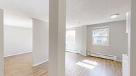 Located at 630 17th Ave SW in Calgary, Alberta, this one-bedroom, one-bathroom unit offers a practical and comfortable single-floor layout. Light wood laminate flooring runs throughout the main living areas, lending warmth and a clean, cohesive aesthetic beneath neutral grey walls.

The open living area benefits from a large window with natural light flooding in, highlighting the baseboard heating and a textured ceiling. The space feels airy and inviting, with room for a variety of furniture arrangements.

The kitchen features white cabinetry with a tile backsplash, a warm wood-toned countertop, and white appliances including a range and overhead hood fan. The layout is efficient, connecting seamlessly to the main living space via an open-plan design anchored by a structural column.

The bedroom is generously proportioned and includes two sets of sliding panel closets, providing ample storage. Light wood flooring continues here, and the neutral palette keeps the room feeling bright and versatile.

The bathroom is well-appointed with a single vanity topped with a warm-toned counter, a large wall mirror, two mirrored medicine cabinets, a full tub-shower surround finished in white tile with a decorative border, and earth-toned floor tiles. Chrome fixtures and towel bars complete the functional, tidy space.

Situated steps from the amenities of 17th Avenue SW, this unit offers convenient urban living in one of Calgary's most walkable neighborhoods.