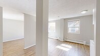 Located at 630 17th Ave SW in Calgary, Alberta, this one-bedroom, one-bathroom unit offers a practical and comfortable single-floor layout. Light wood laminate flooring runs throughout the main living areas, lending warmth and a clean, cohesive aesthetic beneath neutral grey walls.

The open living area benefits from a large window with natural light flooding in, highlighting the baseboard heating and a textured ceiling. The space feels airy and inviting, with room for a variety of furniture arrangements.

The kitchen features white cabinetry with a tile backsplash, a warm wood-toned countertop, and white appliances including a range and overhead hood fan. The layout is efficient, connecting seamlessly to the main living space via an open-plan design anchored by a structural column.

The bedroom is generously proportioned and includes two sets of sliding panel closets, providing ample storage. Light wood flooring continues here, and the neutral palette keeps the room feeling bright and versatile.

The bathroom is well-appointed with a single vanity topped with a warm-toned counter, a large wall mirror, two mirrored medicine cabinets, a full tub-shower surround finished in white tile with a decorative border, and earth-toned floor tiles. Chrome fixtures and towel bars complete the functional, tidy space.

Situated steps from the amenities of 17th Avenue SW, this unit offers convenient urban living in one of Calgary's most walkable neighborhoods.