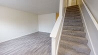 This two-story home in Concord, North Carolina offers a practical and well-organized layout spread across two floors. The main level features light gray wood-look vinyl flooring throughout the living room and kitchen, lending a clean, cohesive aesthetic. The living room is a bright, open space with a window that allows natural light to filter in, while a carpeted staircase with a white railing provides access to the upper level.

The kitchen is efficiently designed with warm-toned wooden cabinetry, dark countertops, and white appliances, including a refrigerator, electric range, and dishwasher. The main level is completed by a full bathroom featuring a tub/shower combination, wood-look flooring, and a vanity with dark countertops.

Upstairs, the two bedrooms are carpeted and offer comfortable proportions. The spacious primary bedroom features two windows that bring in natural light and includes a closet. The second bedroom is equally well-lit and functional. A second full bathroom on this level mirrors the layout of the first, with a tub/shower combination and matching vanity. Textured ceilings are consistent throughout the home, adding to its understated, practical character.
