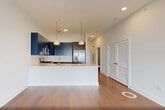 Located at 260 Avenue E in Bayonne, NJ, this well-appointed 2-bedroom, 3-bathroom residence offers a thoughtfully designed single-floor layout. Wide-plank hardwood flooring runs throughout, lending warmth and continuity to every room. The open-concept living, dining, and kitchen area is a standout centerpiece — the kitchen showcases bold navy cabinetry contrasted by dark lower cabinets, a crisp white quartz island with an undermount sink, subway tile backsplash, stainless steel appliances, and stylish pendant lighting. Floor-to-ceiling sliding glass doors flood the living area with natural light and open to panoramic views of the Bayonne skyline and surrounding greenery. The spacious primary bedroom features large windows with outdoor views and benefits from a well-appointed en-suite bathroom with a double-sink vanity, wood-toned cabinetry, and a tiled walk-in shower. A generously sized walk-in closet with built-in shelving adds excellent storage to the primary suite. The second bedroom is bright and versatile, served by its own closets with sliding doors. Three full bathrooms include a tiled tub-and-shower combination. Additional features include four closets, an in-unit laundry area, and a utility room, ensuring ample storage and everyday convenience throughout the home.