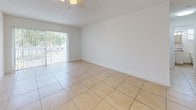 This single-floor unit offers a practical and well-organized layout that maximizes functionality throughout. The living area serves as the central gathering space, finished with large-format beige tile flooring that extends consistently across the entire unit, lending a cohesive, clean aesthetic. A sliding glass door floods the living area with natural light and provides direct access to an outdoor space, complemented by a ceiling fan overhead.

The galley-style kitchen is efficiently designed with cream cabinetry, granite countertops, and a coordinating granite tile backsplash. Stainless steel appliances, including a range, dishwasher, and refrigerator, complete the space. A pass-through window connects the kitchen to the main living and dining area, enhancing the open feel of the layout.

The bedrooms are bright and neutral, each featuring the same tile flooring, white walls, and windows fitted with vertical blinds that allow adjustable natural light. The unit includes two bathrooms, both finished with tile flooring, granite vanity countertops, and tiled tub-surround showers. Small windows in each bathroom provide ventilation and additional natural light. Overall, the space presents a clean, functional, and move-in-ready environment.