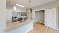 Located at 5067 Elevated View in Hixson, Tennessee, this single-floor residence offers a thoughtfully designed layout with a clean, contemporary aesthetic. The interior is finished with light wood-style flooring throughout the main living areas and hallways, complemented by neutral gray walls and crisp white trim that create a bright, cohesive atmosphere.

The kitchen serves as a central hub, featuring granite countertops, a large island with a built-in sink and pendant lighting overhead, medium-toned cabinetry, stainless steel appliances, and direct access to a walk-in pantry or storage closet. The open layout allows the kitchen to flow naturally into the adjacent living area, which includes a ceiling fan and access to hallway spaces.

The bedrooms are carpeted for comfort and are generously sized, with multiple windows fitted with blinds that invite natural light and outdoor views. Ceiling fans are present in each bedroom, and at least one bedroom includes a walk-in closet with shelving.

The bathrooms are well-appointed, with one featuring a vanity with granite countertops, warm wood cabinetry, and a shower-tub combination. A second bathroom is equipped with accessibility features, including sturdy grab bars, making this residence well-suited for a range of residents. Hallways are wide and navigable, reinforcing the accessible and functional design of the overall floor plan.