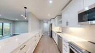 Located at 550 Sheridan Square in Evanston, IL, this well-appointed 2-bedroom, 2-bathroom residence offers a thoughtfully designed single-floor layout with modern finishes throughout. Wide-plank hardwood flooring and recessed lighting flow seamlessly through every room, creating a cohesive and refined aesthetic.

The centerpiece of the home is the expansive galley-style kitchen, featuring floor-to-ceiling white shaker cabinetry with brushed nickel hardware, striking quartz countertops, a full suite of stainless steel appliances, a subway tile backsplash, and a stylish globe pendant light. Generous counter space and abundant storage make this kitchen as functional as it is beautiful.

The open living area is bathed in natural light from a large bank of windows and sliding glass doors that lead to a private balcony with outdoor views — ideal for enjoying the surrounding Evanston neighborhood. The layout creates an airy, expansive feel.

The generously sized primary bedroom offers comfortable proportions and natural light. The second bedroom is well-sized and versatile. Both bathrooms are finished to a high standard; one features a walk-in glass shower with textured white tile, hexagon mosaic floor tile, and elegant brushed gold fixtures.

A dedicated hallway connects all areas of the residence, adding to the home's organized and functional flow.